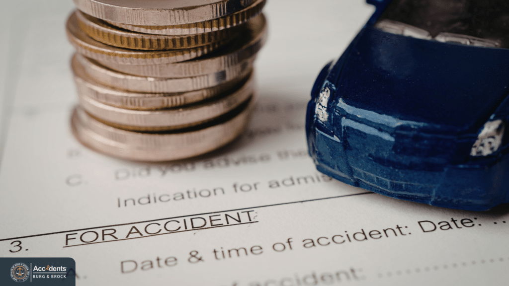 A stack of coins and a small model car resting on an accident insurance claim form.