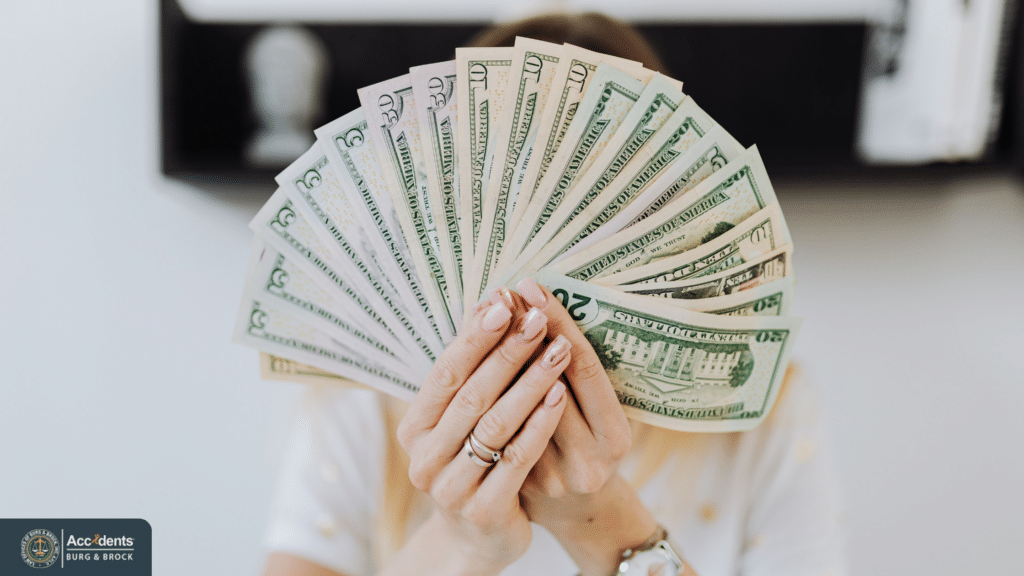 Person holding U.S. dollar bills representing compensation from a personal injury settlement.