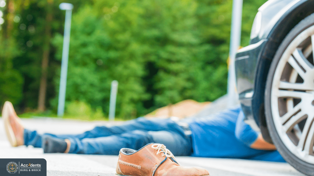 Pedestrian lying on the road beside a car after being struck, with a shoe left on the pavement