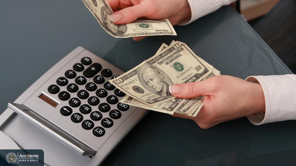 Person counting cash next to a desk calculator
